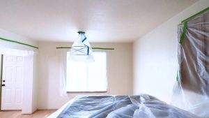 An interior home renovation scene showing rooms prepped with plastic coverings and masking tape